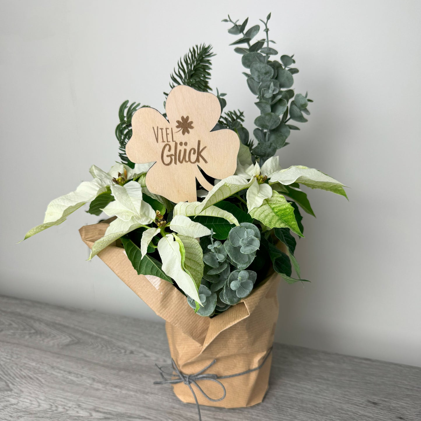 Dekorationsbeispiel: Ein Blumenstecker aus Holz in Form eines Kleeblatts mit der Gravur "Viel Glück" – ein Geschenk, das Glück wünscht.