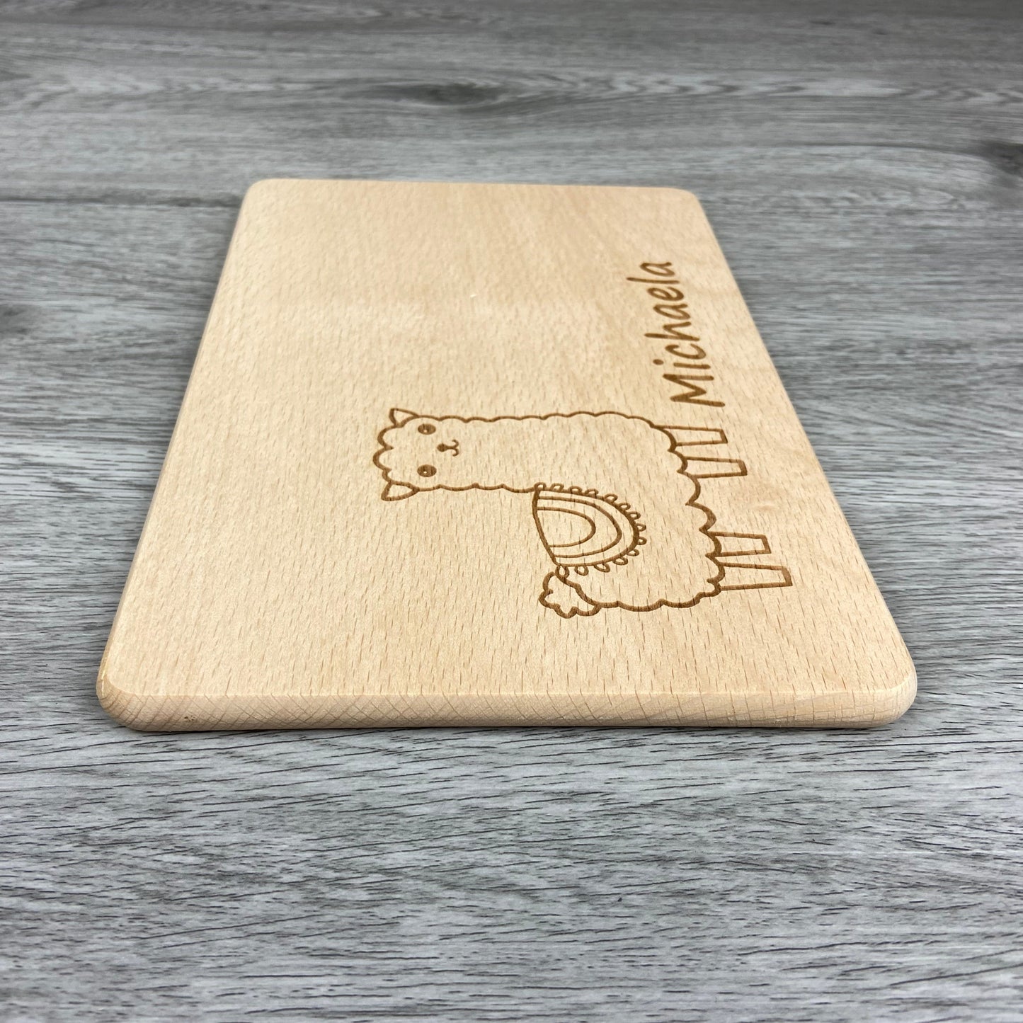 Alpaka Brettchen mit Motiv und Name mit Herz in der Hand personalisiert dank individueller Gravur Affe Zootier Geschenkidee für Kinder zum Geburtstag Taufe Geburt Buchenbrett Holz verschiedene Schriftarten zur Auswahl Detail