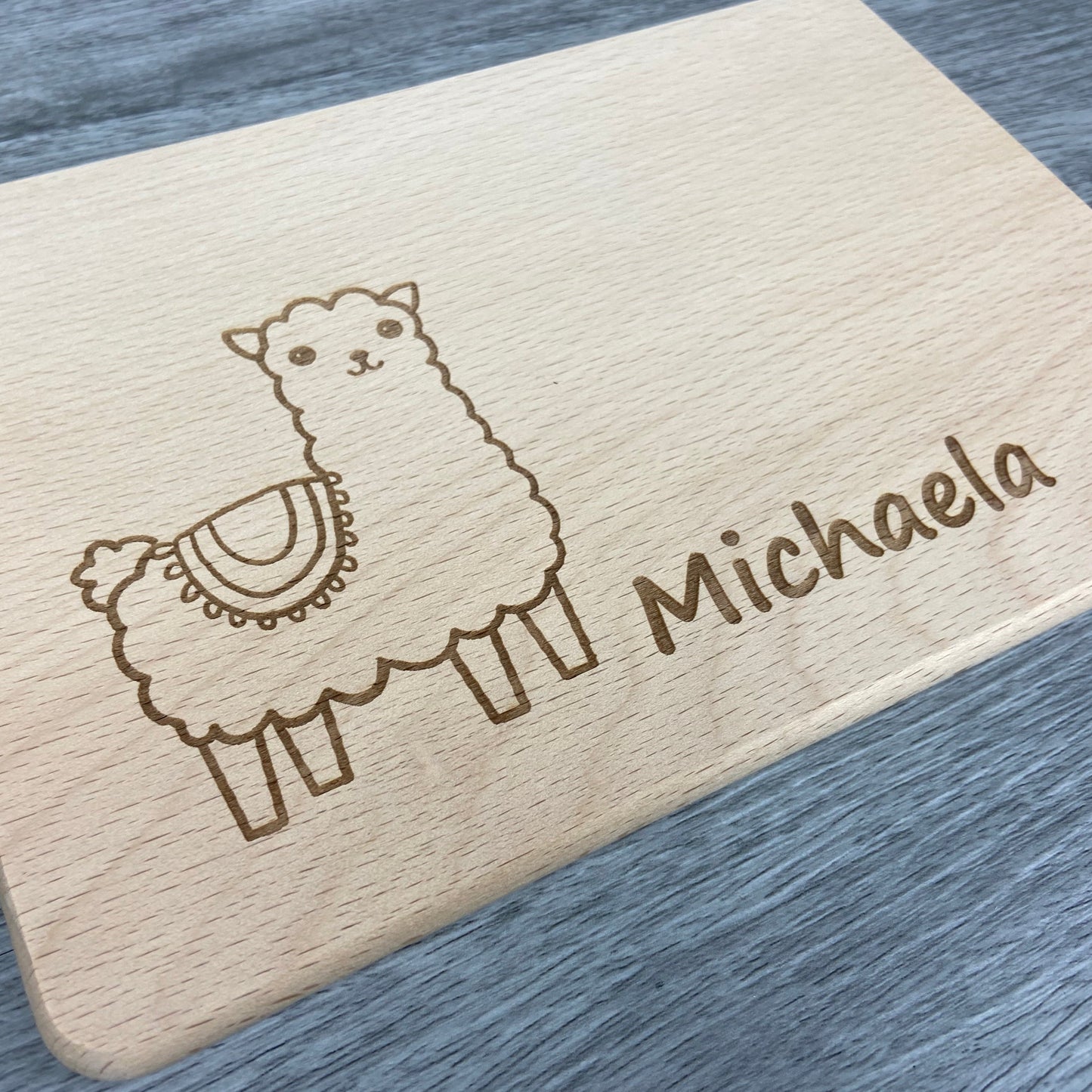 Alpaka Brettchen mit Motiv und Name mit Herz in der Hand personalisiert dank individueller Gravur Affe Zootier Geschenkidee für Kinder zum Geburtstag Taufe Geburt Buchenbrett Holz verschiedene Schriftarten zur Auswahl Detail 1