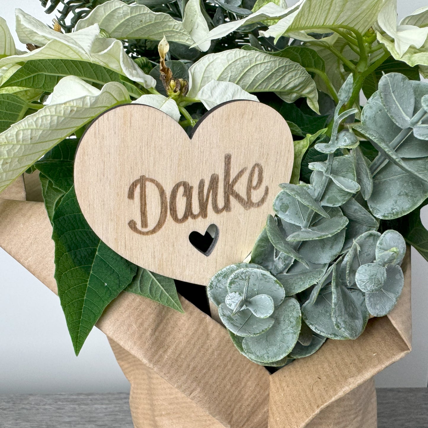 Detailansicht Holz-Blumenstecker in Herzform mit eingravierter Aufschrift "Danke" – ideal für Blumensträuße, Gestecke oder als Dekoration in Topfpflanzen.