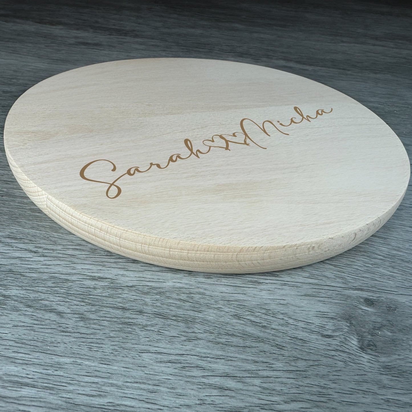Personalisiertes rundes Holzbrett aus Naturholz mit gravierten Namen und Herzmotiv – ideales Geschenk zur Hochzeit oder zum Jahrestag.