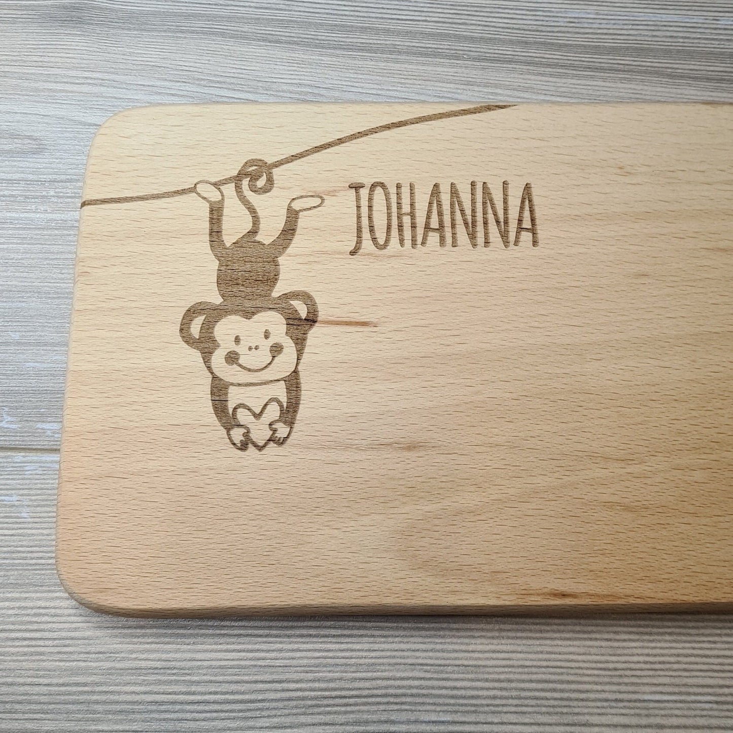 Beispiel Schriftart Brettchen mit Motiv und Name kleines Äffchen mit Herz in der Hand personalisiert dank individueller Gravur Affe Zootier Geschenkidee für Kinder zum Geburtstag Taufe Geburt Buchenbrett Holz verschiedene Schriftarten zur Auswahl