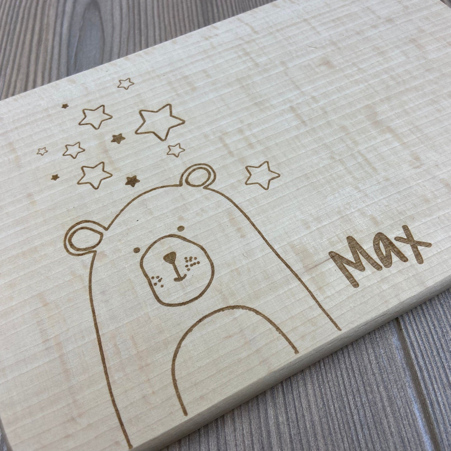 Detailansicht Bär mit Sternen Brettchen mit Motiv und Name personalisiert dank individueller Gravur Braunbär Teddybär Geschenkidee für Kinder zum Geburtstag Taufe Geburt Buchenbrett Holz verschiedene Schriftarten zur Auswahl