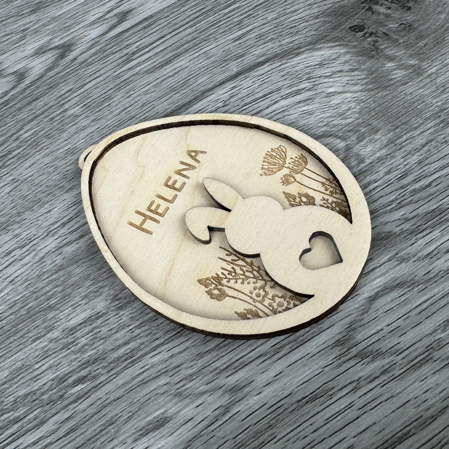 Schrägansicht - Osteranhänger Hase auf Blumenwiese, mit Name personalisiert oder mit dem Text Frohe Ostern Gravur aus Holz, Lasergravur