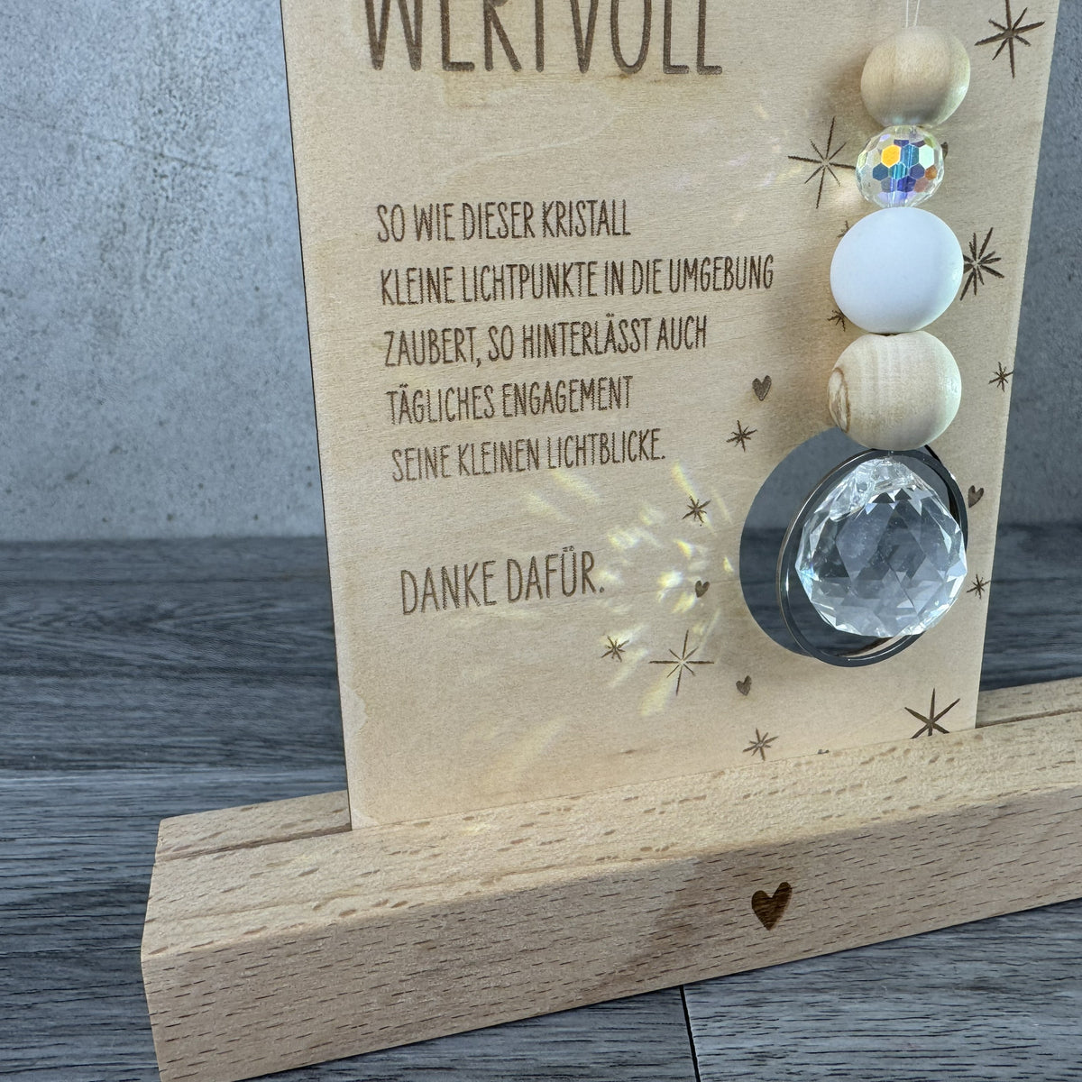 Detailansicht Spruch - Holzkarte mit der Gravur „Besonders wertvoll“, funkelndem Kristall und filigranen Sternmotiven, optional mit passendem Kartenhalter aus Holz – besonderes Dankeschön-Geschenk für Erzieherinnen, Lehrerinnen und liebe Menschen.