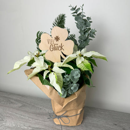 Dekorationsbeispiel: Ein Blumenstecker aus Holz in Form eines Kleeblatts mit der Gravur "Viel Glück" – ein Geschenk, das Glück wünscht.