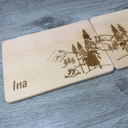 Detailansicht linke Seite - Partnerbrettchen Wandern, Motiv mit Bergen und Wald, Wanderschuhen und Rucksack, mit Namen personalisiert - Geschenkidee für Paare, Freunde, Verliebte Wanderfreunde